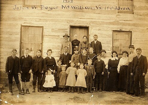Historical photograph of John W. Royce and children from Mount Williams, Virginia, taken in 1901, featuring a large group of adults and children in front of a wooden building.